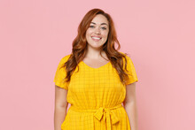 Smiling Beautiful Attractive Young Redhead Plus Size Body Positive Female Woman Girl 20s In Yellow Casual Dress Posing Looking Camera Isolated On Pastel Pink Color Wall Background Studio Portrait.