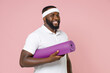 © ViDi Studio - Smiling young bearded african american fitness sports man in white headband t-shirt posing hold yoga mat looking camera spending time in gym isolated on pastel pink color background studio portrait.