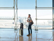 © Cavan Images - young woman with suitcase talking on phone while waiting for flight