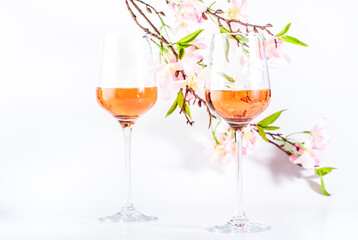 Rose wine glass with bottle on the white table and pink flowers. Rosado, rosato or blush wine tasting in wineshop, bar concept. Copy Space