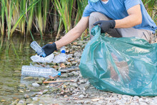 Close Up Of Person Collecting Plastic From The River.