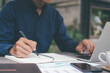 © Cavan Images - Closeup businessman writing hand and using computer.