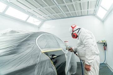 Wall Mural - Automobile painting. Car painter with gun in chamber. Spray operation. 