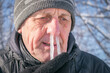 The man's snot was frozen in his nose. Portrait of an elderly man with icicles in his nose. Runny nose in the winter forest. Frosty weather in winter. Comic concept of a winter cold.