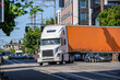 Big rig semi truck with long dry van semi trailer turning on the crossroad street intersection with busy city traffic
