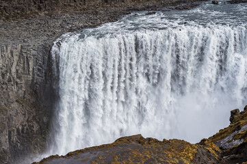 Two men standing near Dettifoss waterfall in Iceland.