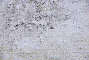 The texture of the old brick wall painted white with peeling paint