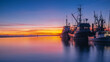 Seashore bay view with colourful sunset blue purple orange sky and clouds boats ships in dock