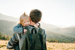 © Serhii - The daughter hug parent on nature. Dad with backpack and child walk in the autumn grass. Family spending time together in mountain outside, on vacation. Holiday trip concept. World Tourism Day.