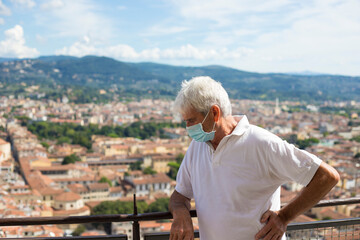 Wall Mural - Senior mature man, wearing face mask due to covid-19 pandemic, on the balcony of the Florence dome, in Santa Maria del Fiore cathedral. Tuscany, Italy.