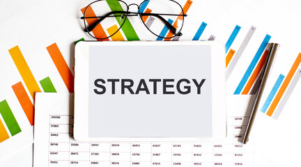 Poster - The tablet with text STRATEGY on business charts,glasses and pen
