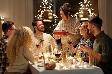 holidays, celebration and people concept - happy smiling friends having christmas dinner at home in 