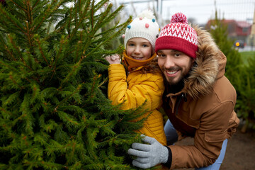 Poster - family, winter holidays and people concept - happy father and little daughter choosing christmas tree at street market