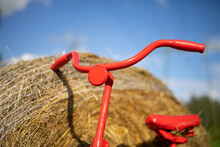 Front Headlight On Steering Wheel Of Red Decorative Bicycle By The Roll Of Hay On Background.