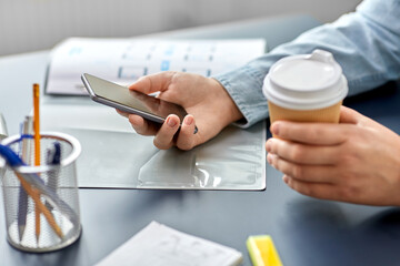 Wall Mural - business, technology and people concept - close up of hands using smartphone and drinking takeaway coffee from paper cup at office