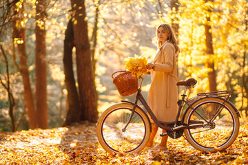 Autumn woman in autumn park. Happy young woman posing with bike in autumn forest.