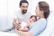 © nareekarn - smiling mother and father holding their newborn baby at home..portrait of happy family at home, young parents holding on hands little sweet newborn baby, love and happiness concept.