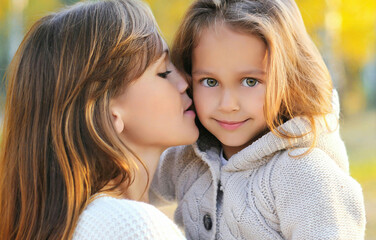 autumn portrait of happy mother kissing her daughter child