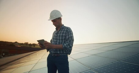 Wall Mural - an young engineer is checking with tablet an operation of sun and cleanliness on field of photovolta