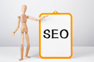 Poster - wooden man shows with a hand to white board with text seo