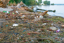 Plastic Trash And Garbage On Polluted Shoreline And Beach By Water's Edge