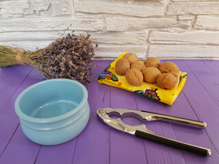 Walnuts, a nut splitting tool, a sprig of lavender and a blue Cup on a purple background