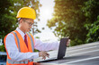 © Pituk - Portrait of Asian engineer in safety helmet using laptop checking solar panels outdoors.