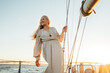 © Artem Varnitsin - Attractive senior female in long dress looking away outdoors. Caucasian mature woman standing on a sailboat deck.