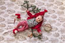 Little Baby In Bright Clothes With Christmas Tree Branches