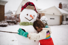Child Hugs Snowman With Hat, Scarf, Gloves And Carrot Nose