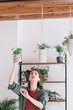 © Alberto Bogo/Stocksy - Curly Girl Hanging Small Plant In Recycled Plastic Pot On The Wall