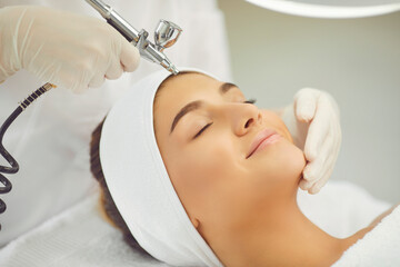 smiling womans face getting oxygen therapy or jet peeling from cosmetologist