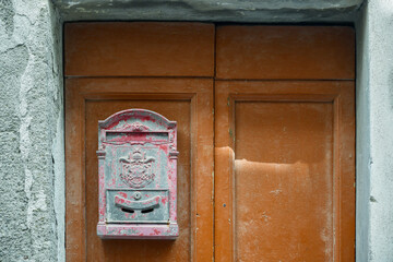 Sticker - Close-up of an old, worn out mailbox hanging on the wooden front door of an old house, Italy