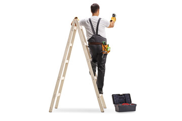 Wall Mural - Rear view shot of a repairman on a ladder drilling with a machine into a wall
