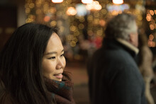 An Asian Girl Wearing A Scarf And White Jacket Watches The Light Display And Christmas Carols In Front Of The Bystanders On George Street, Edinburgh, UK, During The Christmas Celebrations And Festive 