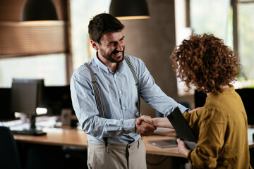 Businesswoman and businessman discussing work in office. Two friends handshake in office..