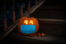 Lighted Carved Jack-o-Lantern Dressed Up For Halloween With COVID Pandemic Face Mask