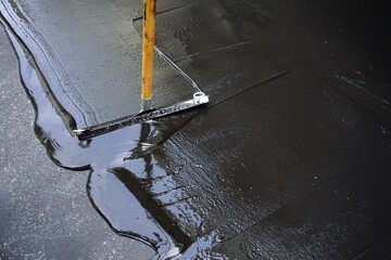 Man sealing asphalt driveway/Sealcoating