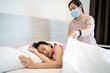 © Satjawat - Sick female people sleeping on a bed in bedroom,asian mother in a mask cover child girl patient with blanket,putting up the blanket on her daughter at home,health care,love,family relations concept.
