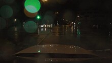 Waiting For The Green Light Of An Traffic Light And Then Starting To Drive With A Car At A Rainy Night In A City With Oncoming Traffic.