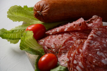 Wall Mural - A selection of spicy dried or smoked  sausages on lettuce leaves with cherry tomatoes