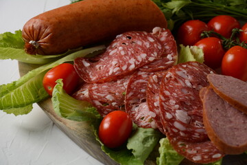 Wall Mural - A selection of spicy dried or smoked  sausages on lettuce leaves with cherry tomatoes