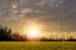 © mark_gusev - Camogie, hurling and rugby tall goalpost on a training pitch at sunset. Low angle of view. Sun flare and warm sunset sky. Irish National sports concept. Nobody.