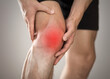 © OB production - Pain in the knee of a man. Highlighted in red. On a gray background. Close up
