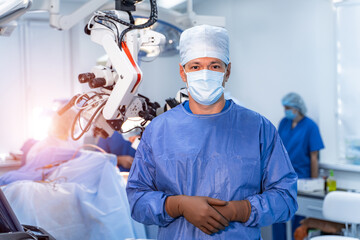 Neurosurgeon posing to the camera in operating theater. Surgery operation. Group of surgeons in operating room with surgery equipment in the background. Medical background, selective focus.