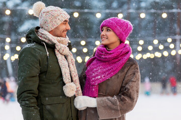 Poster - people and leisure concept - happy smiling couple talking at outdoor skating rink in winter