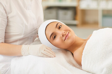 Wall Mural - Smiling young woman looking at camera after procedure of facial massage