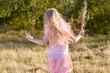 © Olga Koroleva - Portrait of a girl with long hair, in a light dress, running away in the green grass, nature on summer vacation. Playing in the park at sunset.