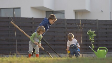 Three kids with spade digging the soil in the garden