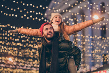 Photo Of Positive Couple Having Fun Christmas X-mas Around Evening Outside Illumination Boyfriend Piggyback Girlfriend Holding Hands Fly